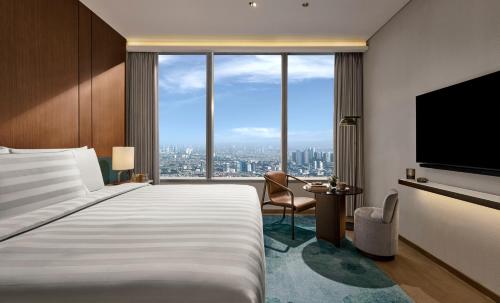 a hotel room with a bed and a large window at Pan Pacific Jakarta in Jakarta