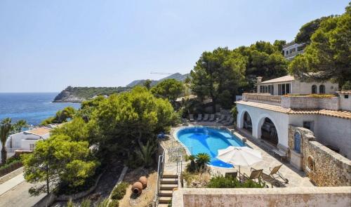 an external view of a house with a swimming pool and the ocean at Unglaubliche Villa mit Meerblick und Pool in Font de Sa Cala