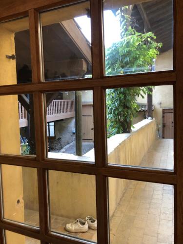 a view through a window looking out at a courtyard at La Thibaude - Maison Vigneronne à Charly (proche Lyon) in Charly