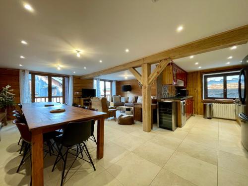Il dispose d'une cuisine et d'un salon avec une table et des chaises en bois. dans l'établissement Homency - Chalet La Montagne du Prégentil, à L'Alpe-d'Huez