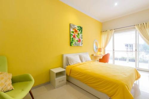 a yellow bedroom with a bed and a chair at Villa Omah Ayu Mendiro in Ngemplak