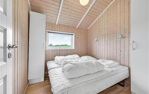 a bedroom with a bed with white sheets and a window at Holiday Home Skovridervænget Rudkøbing Xi in Spodsbjerg