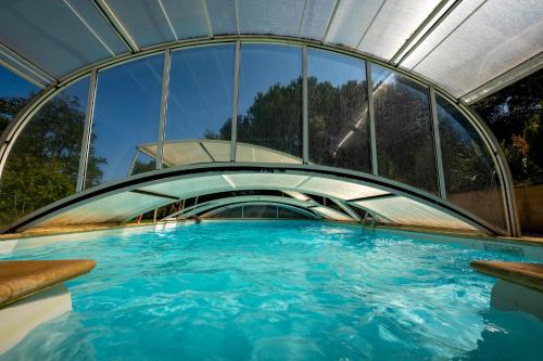 a swimming pool in a building with a bridge at La Maison de l'écolieu du Turc - Piscine partagée in Le Mas-dʼAgenais