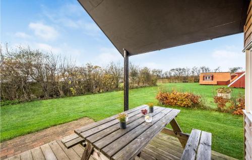 - une table de pique-nique en bois sur une terrasse avec vue sur un champ dans l'établissement 2 Bedroom Amazing Home In Ulfborg, à Ulfborg