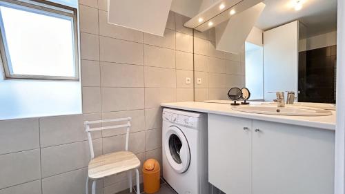 une salle de bain avec une machine à laver et un lavabo dans l'établissement Le calypso de la Baie, au Crotoy