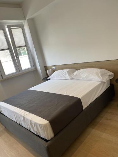 a large bed in a bedroom with two windows at Sirolo appartamenti in Sirolo
