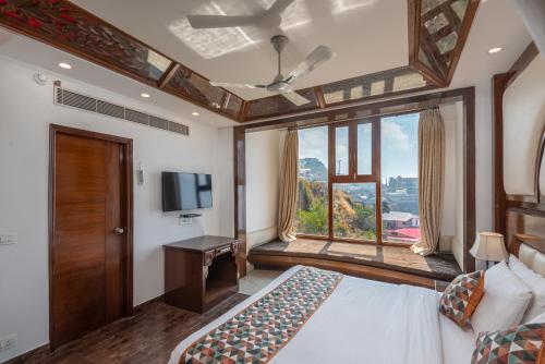 a bedroom with a bed and a tv and a window at Lawrence Solitaire Resort, Mall road, Mussoorie in Mussoorie