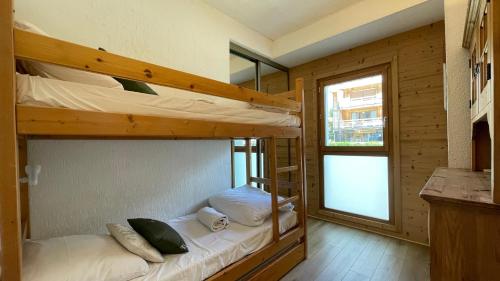 a bedroom with two bunk beds and a window at Homency - Résidence Ménandière W1 in L'Alpe-d'Huez