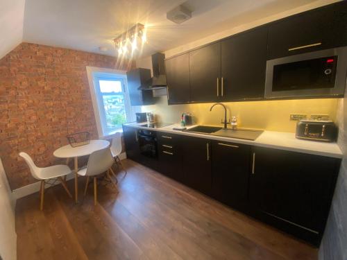 a kitchen with black cabinets and a table with chairs at Central Apartments - Derelict in Blairgowrie