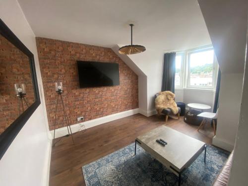 a living room with a tv on a brick wall at Central Apartments - Derelict in Blairgowrie