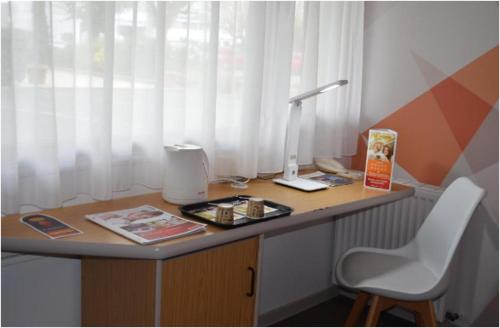 a desk with a lamp and a chair in a room at initial by balladins La Roche-sur-Yon in La Roche-sur-Yon
