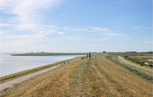 a group of people walking down a dirt road next to the water at 4 Bedroom Cozy Home In Heinkenszand in Heinkensand