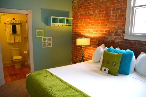 1 dormitorio con 1 cama con pared de ladrillo en Grand Highland Hotel en Prescott