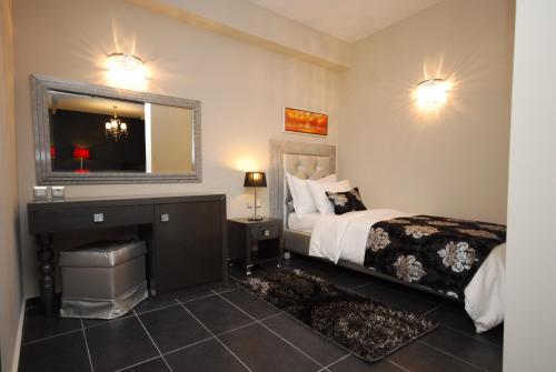 a bedroom with a bed and a vanity and a mirror at 4 Epoxes Hotel Spa in Kato Loutraki