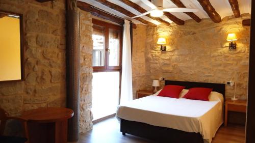 a bedroom with a bed with red pillows and a window at Alojamiento La Fresneda in La Fresneda