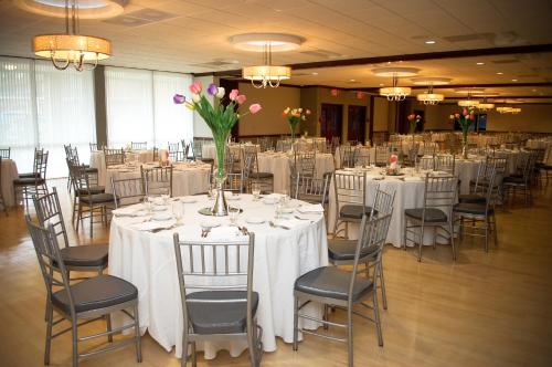 un salón de banquetes con mesas blancas, sillas y flores en Unique Suites Hotel, en Charleston