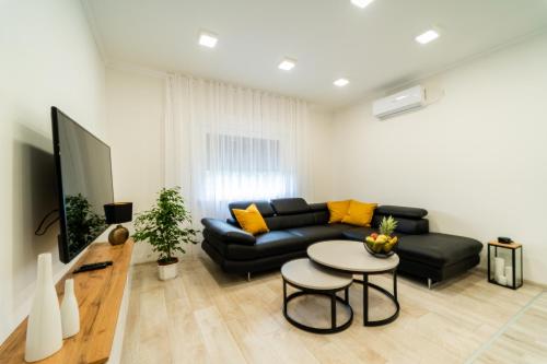 a living room with a black couch and a table at Apartman Domy in Kozljak