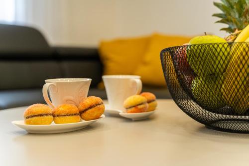 two cups and plates of donuts on a table at Apartman Domy in Kozljak