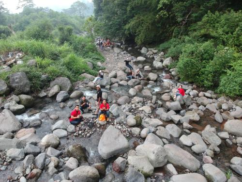 a group of people sitting around a fire in a river at Leuweung Geledegan Ecoldge in Kiarapayung 2