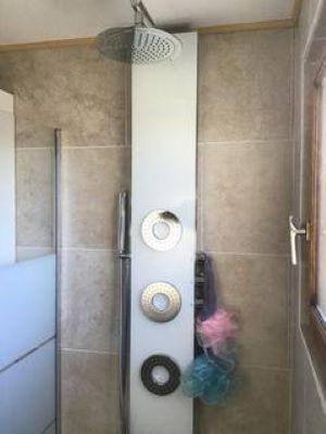 une douche dans une salle de bain avec une porte vitrée dans l'établissement Maison au calme, à Saint-Quentin-la-Poterie