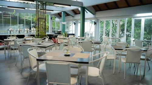 a dining room with tables and white chairs at Leuweung Geledegan Ecoldge in Kiarapayung 2