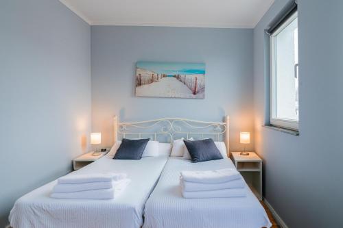 a bedroom with two beds with white sheets and two lamps at CBlue "Apartmenthaus Chrischanshof" in Warnemünde