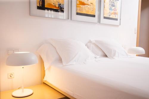 a bedroom with a white bed with paintings on the wall at Hotel Nou Rom&agrave; in Denia