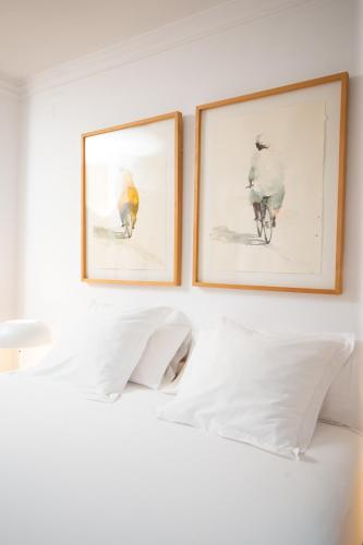 two framed pictures on a wall above a bed at Hotel Nou Romà in Denia
