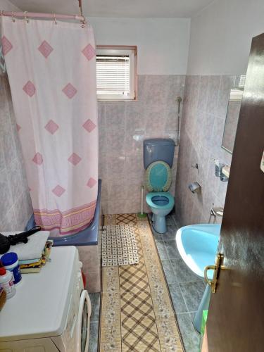 a bathroom with a toilet and a shower curtain at Stefin kutak HOME in Bosanski Novi