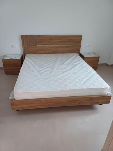 a bed with a wooden frame and white mattress at Mary Apartments in Stalís