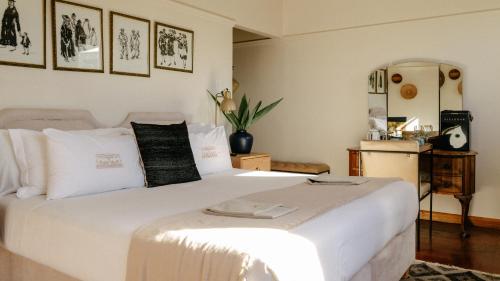 a bedroom with a large white bed and pictures on the wall at Sonnekus Boutique Hotel & Bistro in Kalk Bay