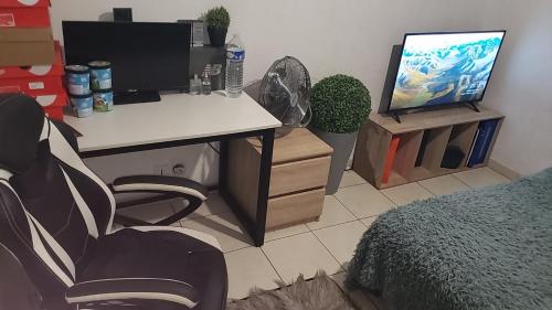 a room with a desk with a computer and a tv at Le plais de la ville historique in Drancy