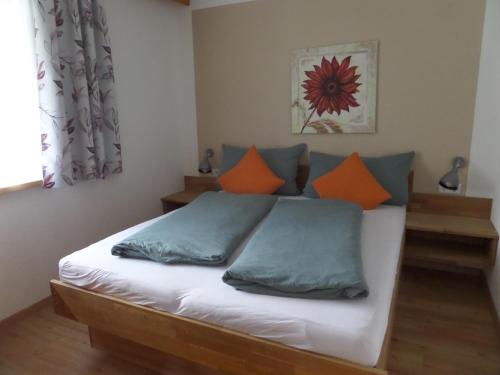 a bedroom with a bed with orange and blue pillows at Haus Regenbogen in Pertisau