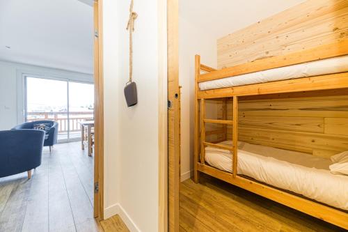 a bedroom with two bunk beds and a dining room at Homency - Résidence de l'Alpe 30 in L'Alpe-d'Huez