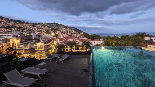 a swimming pool with a view of a city at night at Chic Two-Bedroom En Suite in Central Town - Savoy Residence in Funchal