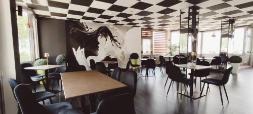 a restaurant with tables and chairs and a painting on the wall at Hotel Everest Arco in Arco