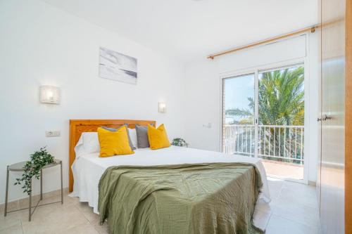 a white bedroom with a large bed with yellow pillows at Jouvacations Villa 2 Freser con piscina compartida in Empuriabrava