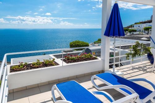 a balcony with chairs and an umbrella and the ocean at Bahia Blanca in Puerto Rico de Gran Canaria