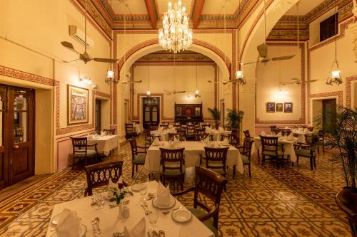 a dining room with tables and chairs and a chandelier at Umed Bhawan Palace, Kotah in Kota