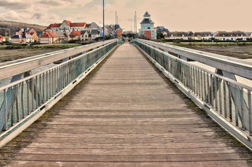 a bridge over the water with a town in the background at Port-Guillaume, résidence de vacances avec mer & piscine in Dives-sur-Mer