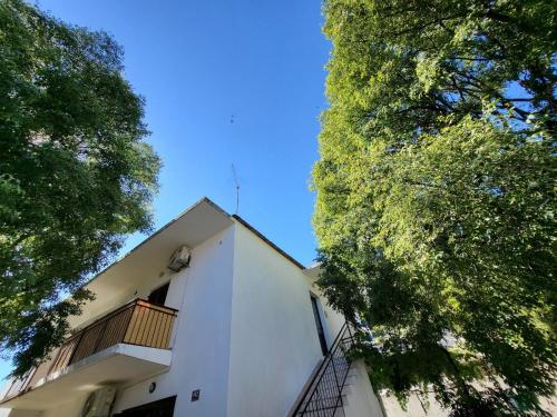 a white building with a balcony and trees at Apartman Meri B - GORNJI in Drvenik