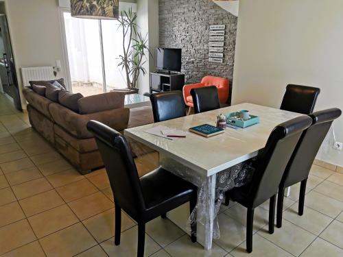 un salon avec une table avec des chaises et un canapé dans l'établissement Le Patio Celeste, à Les Sables-dʼOlonne