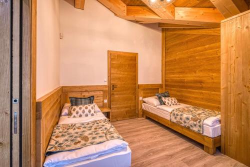 two beds in a room with wooden walls at CHALET MOUNTAIN in Demanovska Dolina