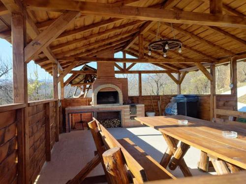 an outdoor kitchen with wooden tables and a fireplace at Cabana Măgura in Măgura