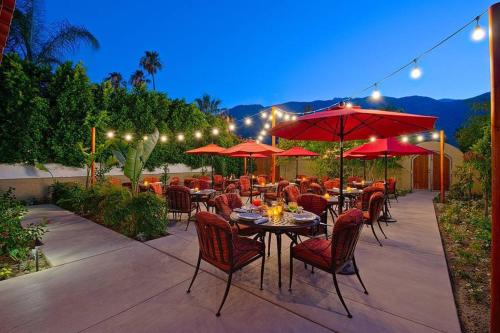 a patio with tables and chairs and red umbrellas at Los Arboles Hotel in Palm Springs