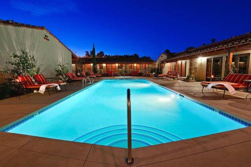 a swimming pool with chairs and a house at Los Arboles Hotel in Palm Springs