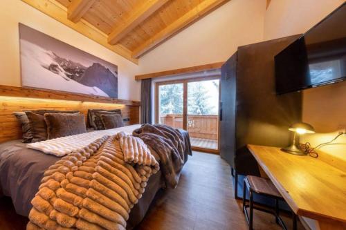 a bedroom with a bed and a desk with a television at Chalet Zillertal Arena 1 in Kirchdorf