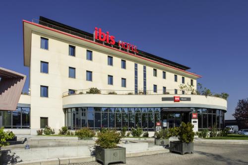 a large white building with a red sign on it at Ibis Valladolid in Valladolid