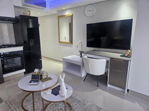 a living room with two tables and a large screen television at VIP Goldroom The Millennial Umhlanga in Durban