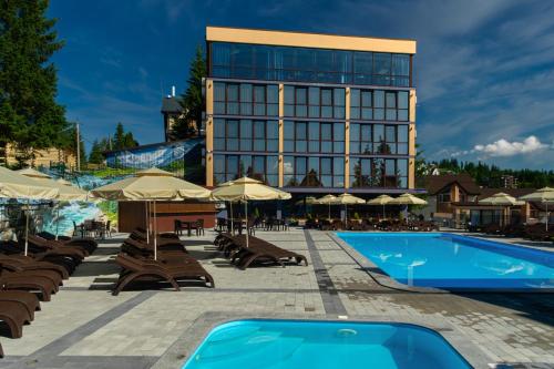 a hotel with a pool and chairs and a building at Summit in Yablunytsya
